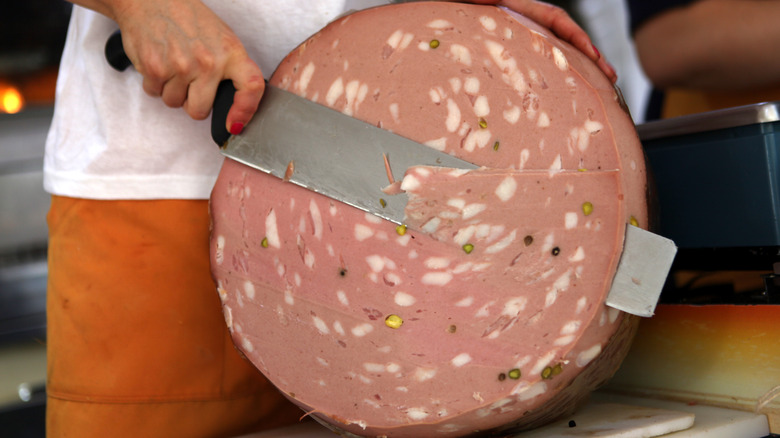 Person slicing mortadella