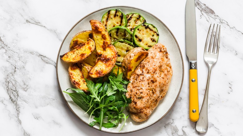 Cooked chicken breast with roast potatoes and vegetables