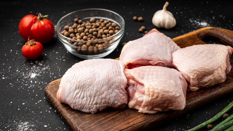 Raw chicken thighs on a wooden tray