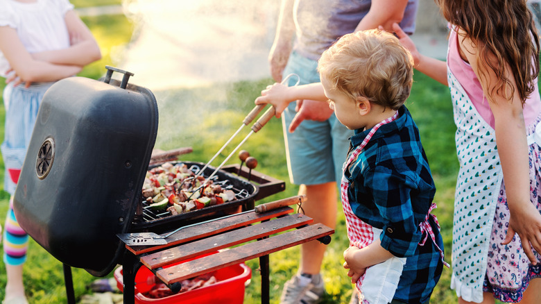 Child in apron helping to grill food