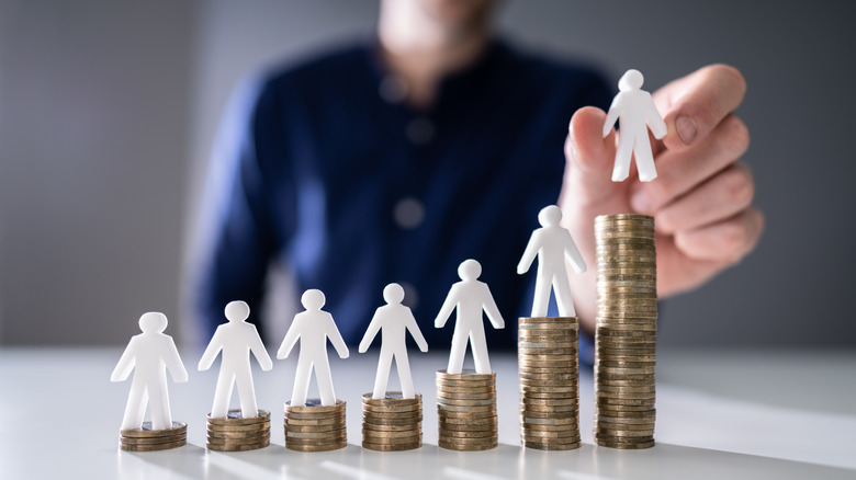 Person placing plastic figure on tall stack of coins