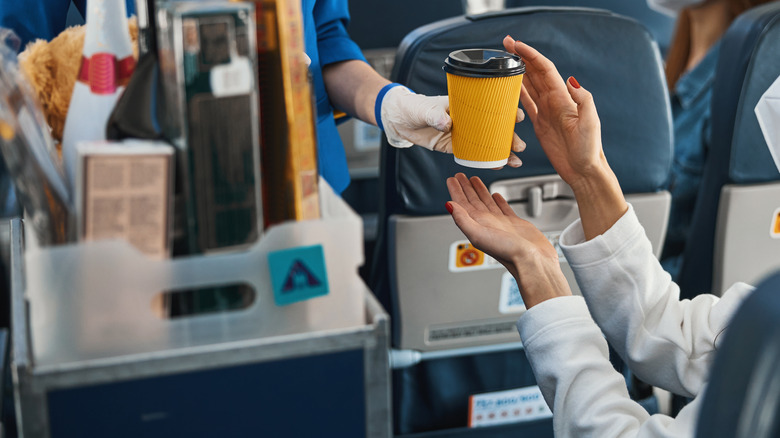 flight attendant handing passenger coffee