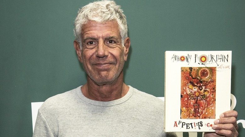 Anthony Bourdain holding his cookbook