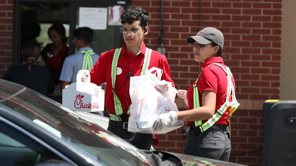 Glove wearing Chick-fil-A staff deliver pick-up orders curbside