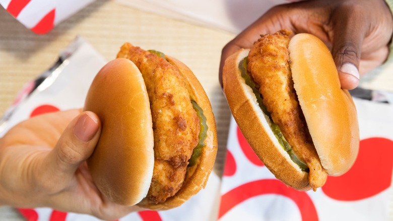 Two people holding Chik-Fil-A sandwiches