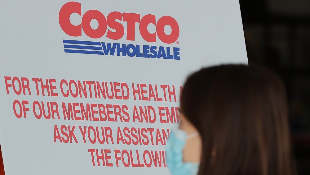 New temporary policies posted in Costco entrance with masked shopper