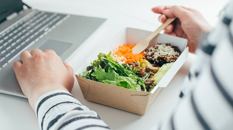 Person eating in front of laptop