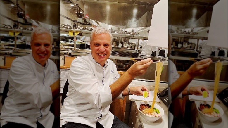 Eric Ripert smiling with a bowl of noodles