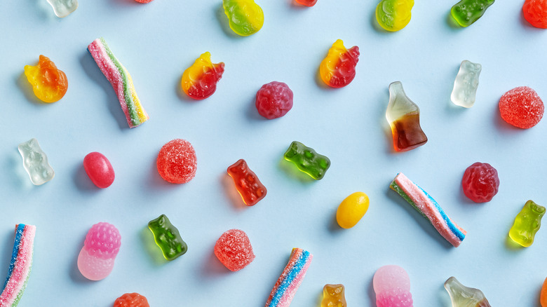 Jelly beans and various gummy candies on blue background