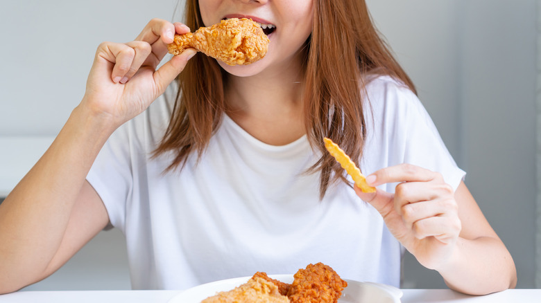 woman smiling while eating fried chicken