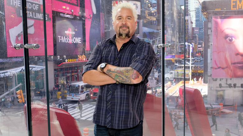 Guy Fieris posing in front of a window in a Times Square building