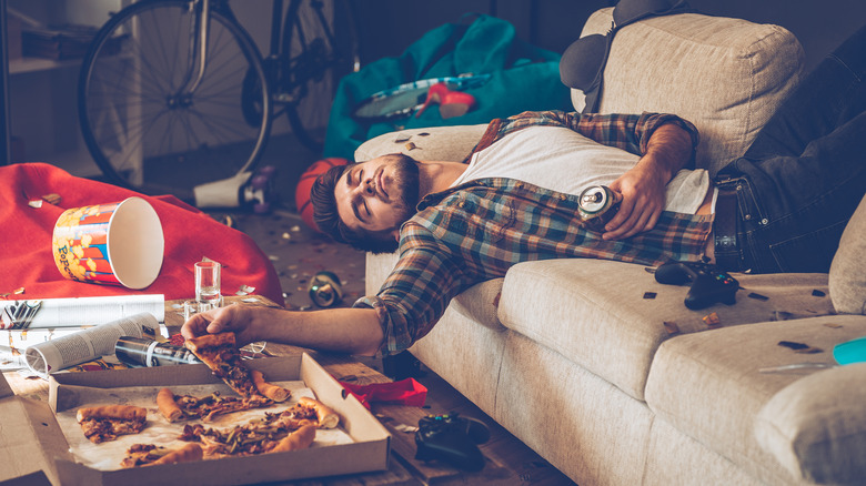 Hungover man on a couch with pizza