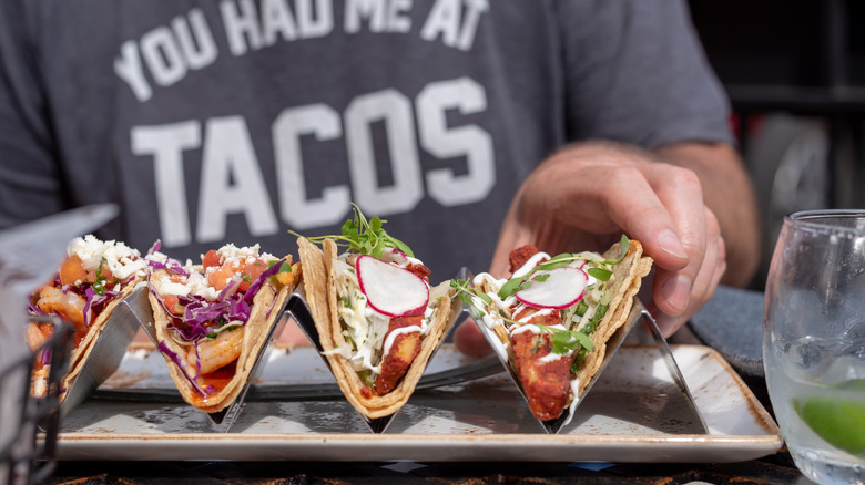 Man reaching out to grab a taco