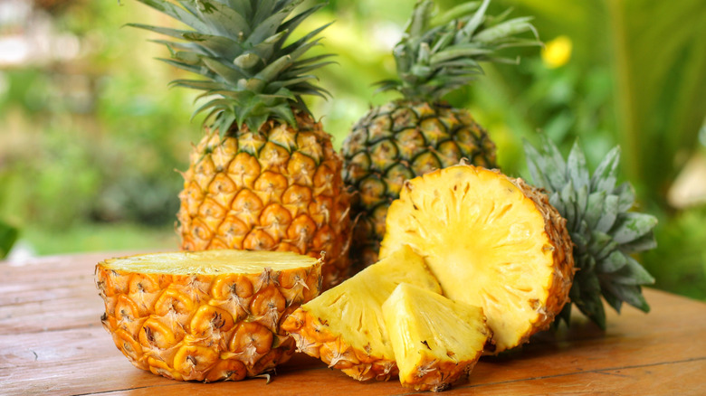 Whole and sliced pineapples on a wooden table