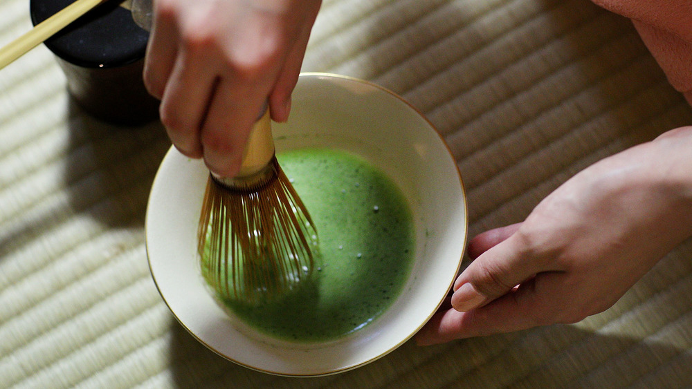 hands preparing matcha with whisk