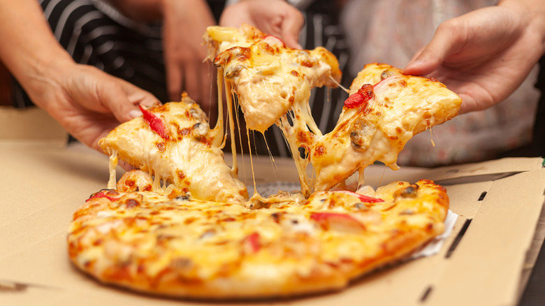 Hands pulling apart slices of pizza