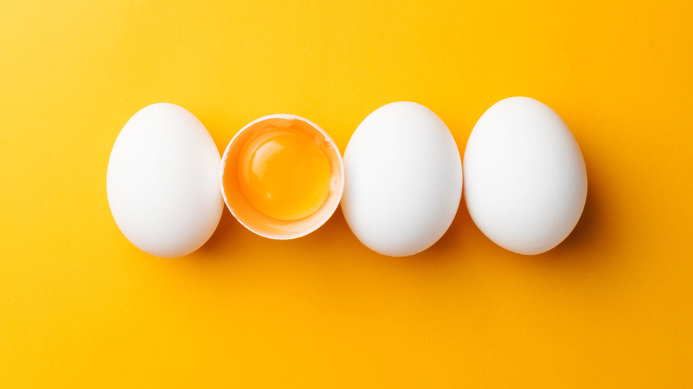 White eggs in a row, with one yolk on a yellow background