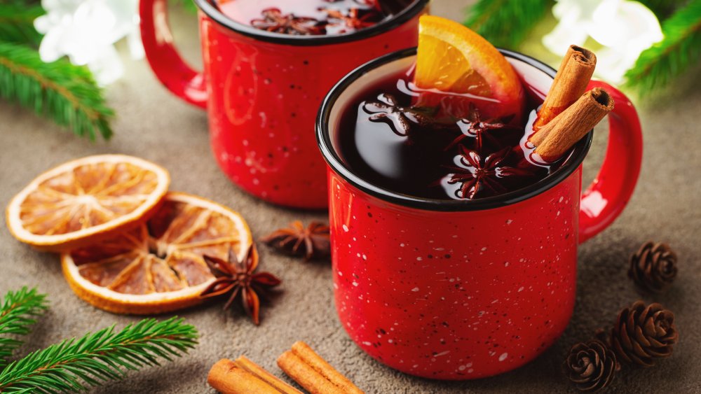 Red mugs of Glühwein with cinnamon sticks, orange, and star anise