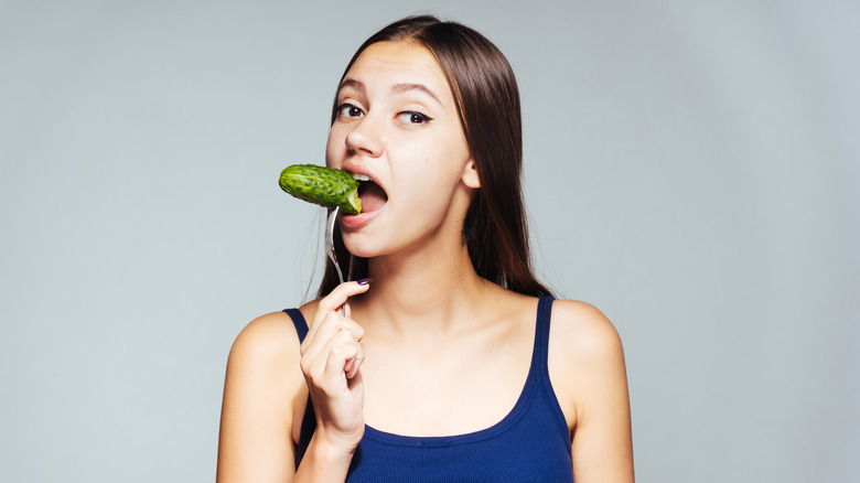 woman enjoying a pickle on a fork