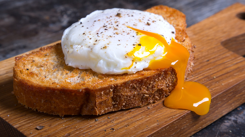 A runny egg spilling its yolk over toast