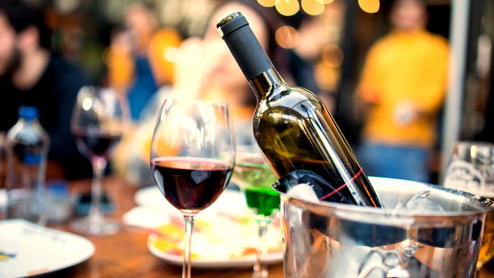 glass of red wine next to a bottle in an ice bucket