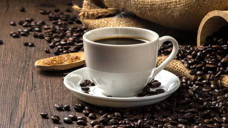 coffee in a cup surrounded by coffee beans