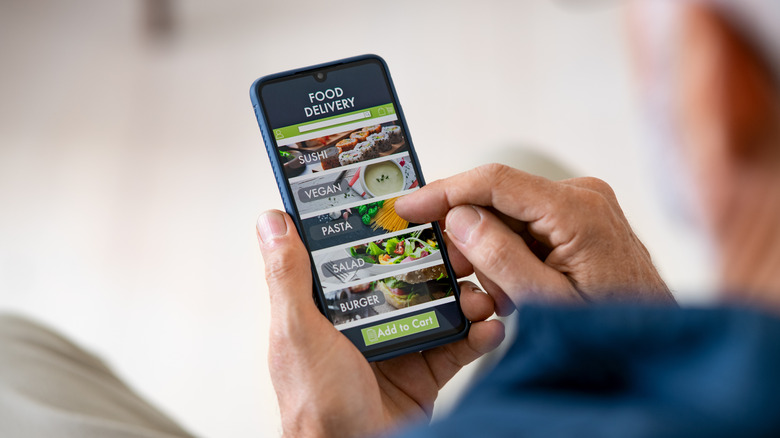 person holding phone with food delivery app on screen