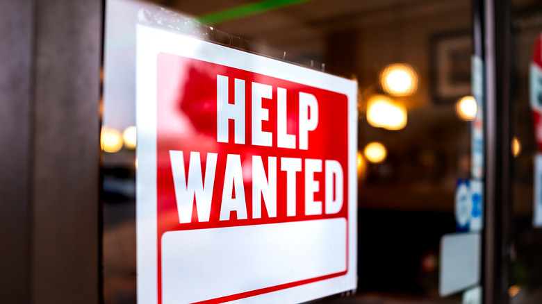 Red and white "help wanted" sign in window