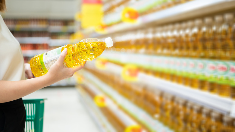 Person holding vegetable oil in grocery aisle