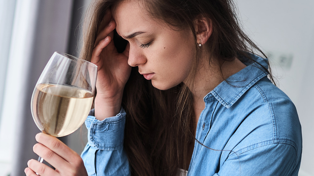 woman with glass of white wine and headache