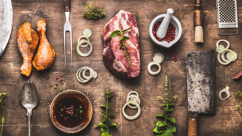 Chicken and steak with various grilling tools and marinades