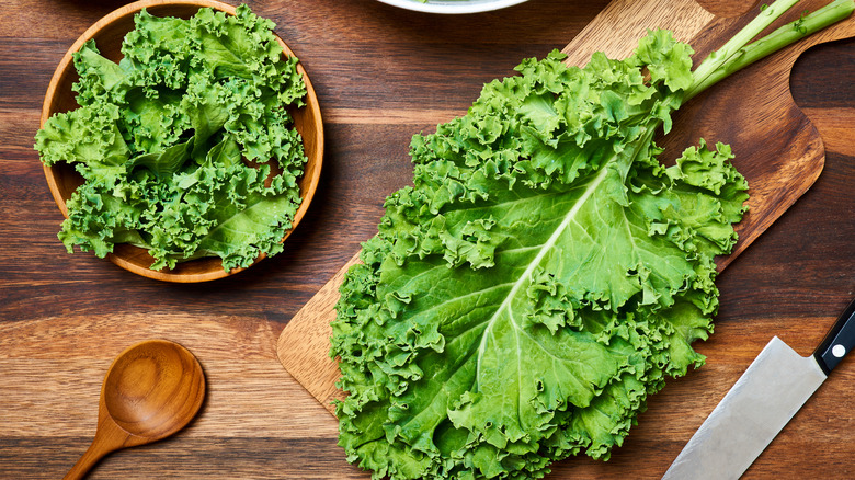 Kale in a wooden bowl and on a chopping board 