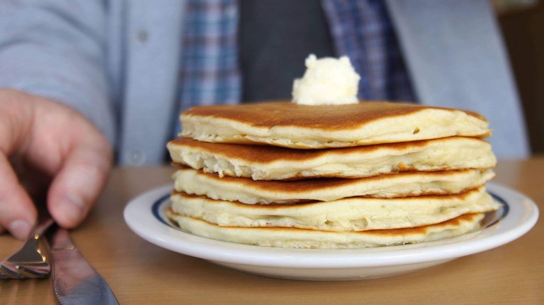 Person in front of stack of pancakes