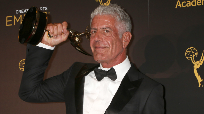 Tanned Anthony Bourdain holding Emmy