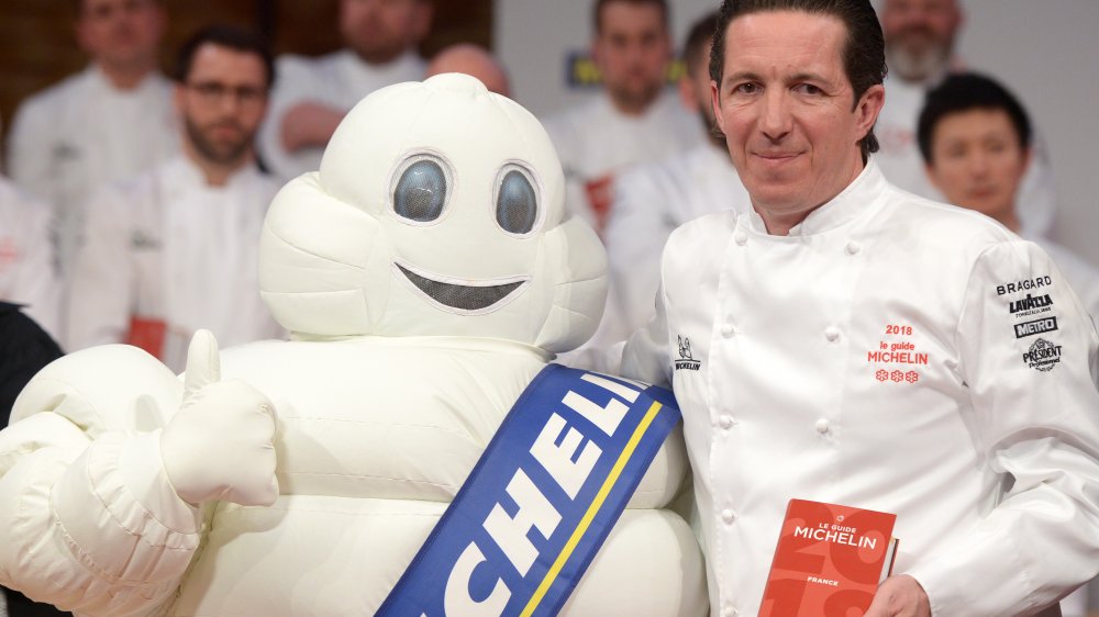 Michelin mascot and chef holding Michelin Guide