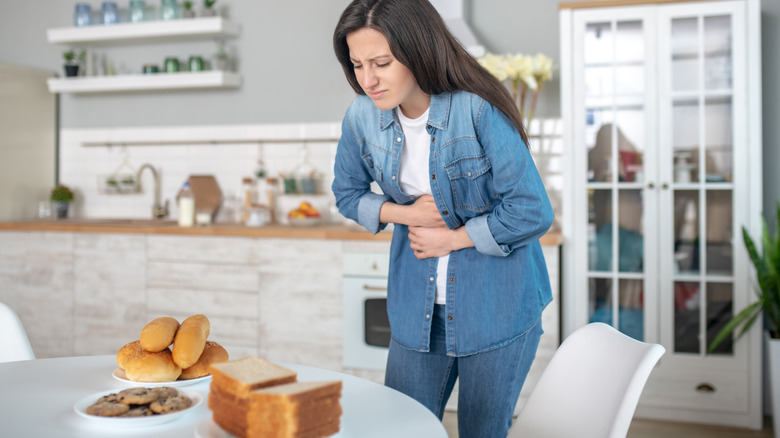 Person grimacing and holding stomach 