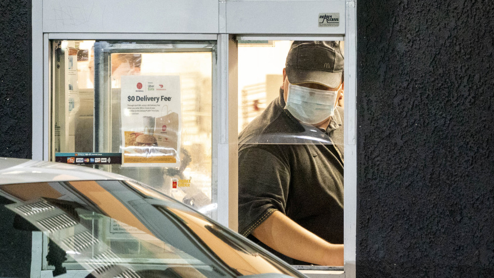 Masked employee at a McDonald's drive through