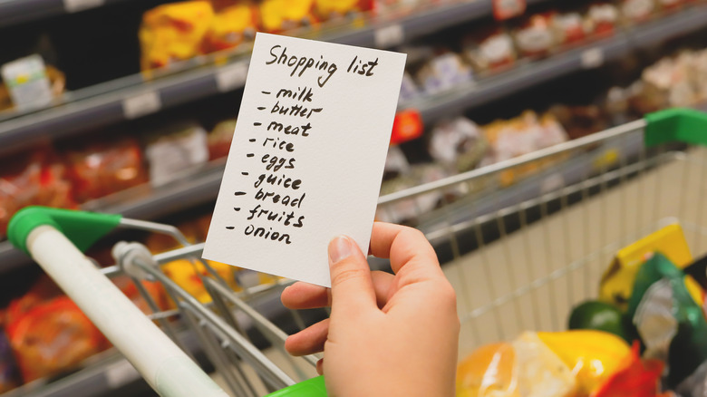 person grocery shopping with shopping list