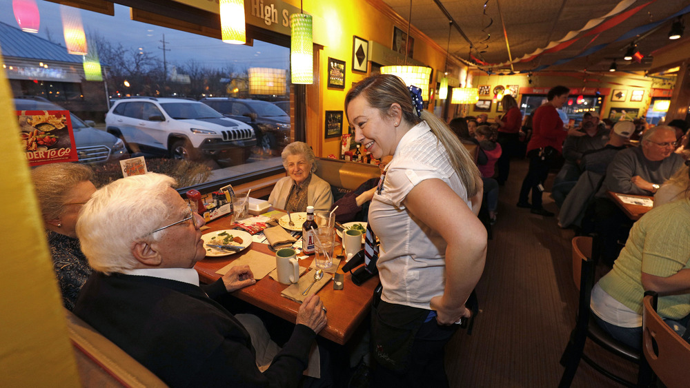 A server talks with a customer at their table