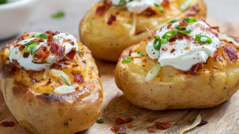 Baked potatoes topped with sour cream, bacon, and chives