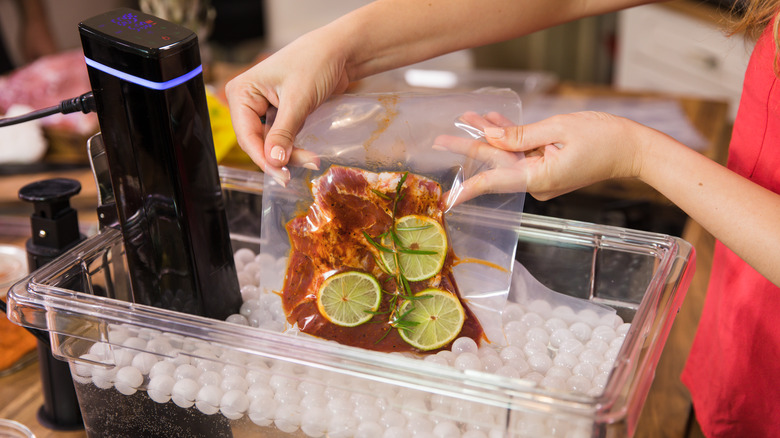 Person putting meat into a clear tub