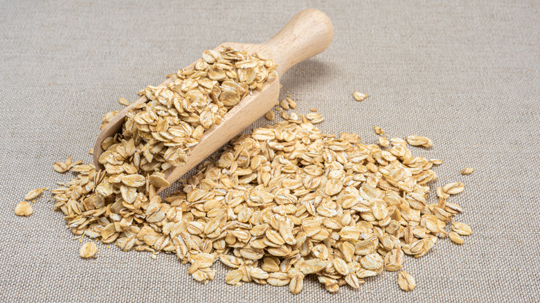 Raw oats next to wooden scoop