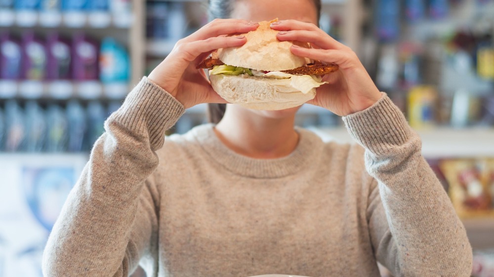 woman eating a sandwich at a gas station cafe