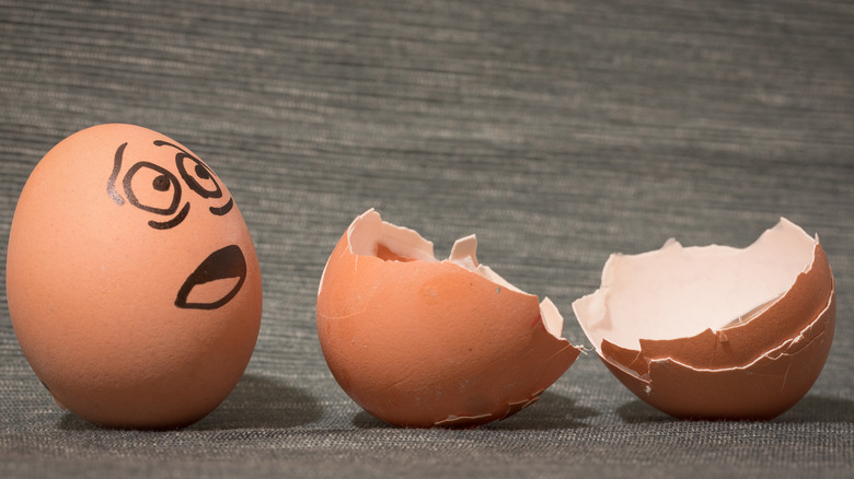 Frightened egg with face on it looking at cracked shells