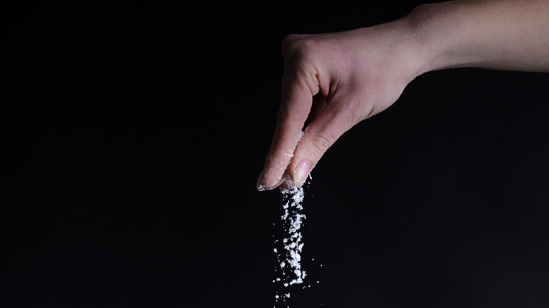 Hand sprinkling coarse salt