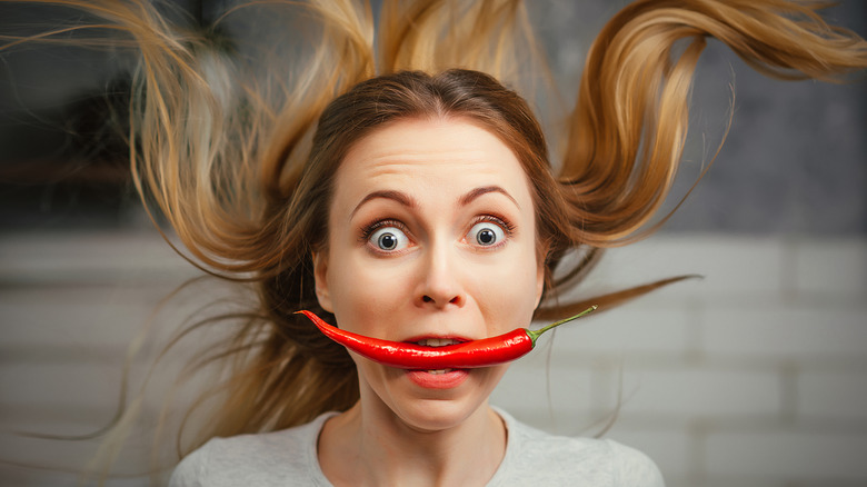 Woman with chile pepper in mouth