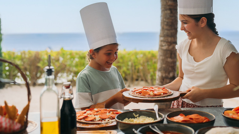 Two kids making a pizza together at a tropical location