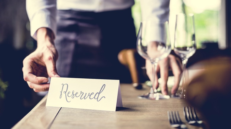 Waiter setting out reserved card on table