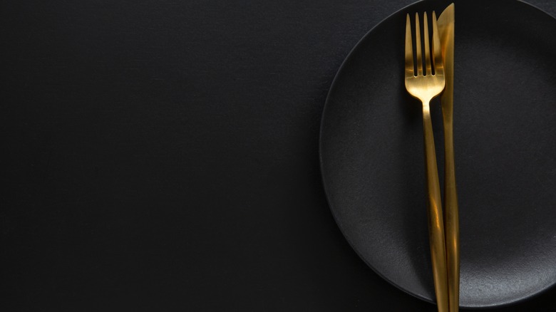 Gold silverware on a black plate