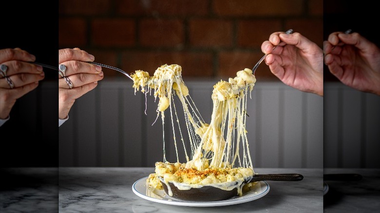 A very cheesy dish being shared by two 